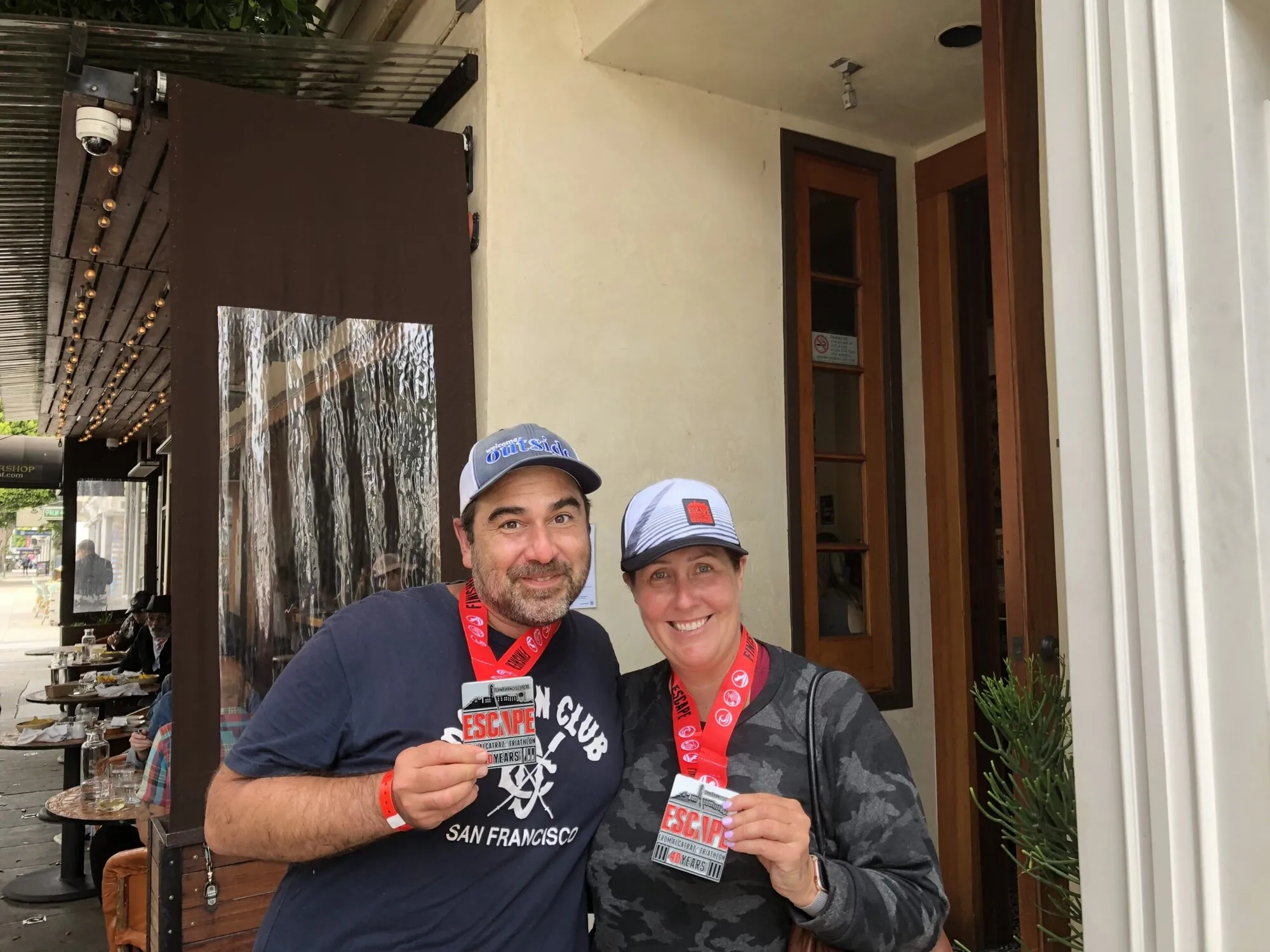 Kenda and a friend in matching caps, holding up their medals after the Escape from Alcatraz triathlon
