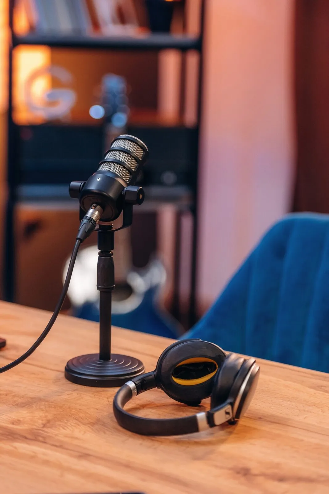 A podcast microphone and headphones on a wooden desk