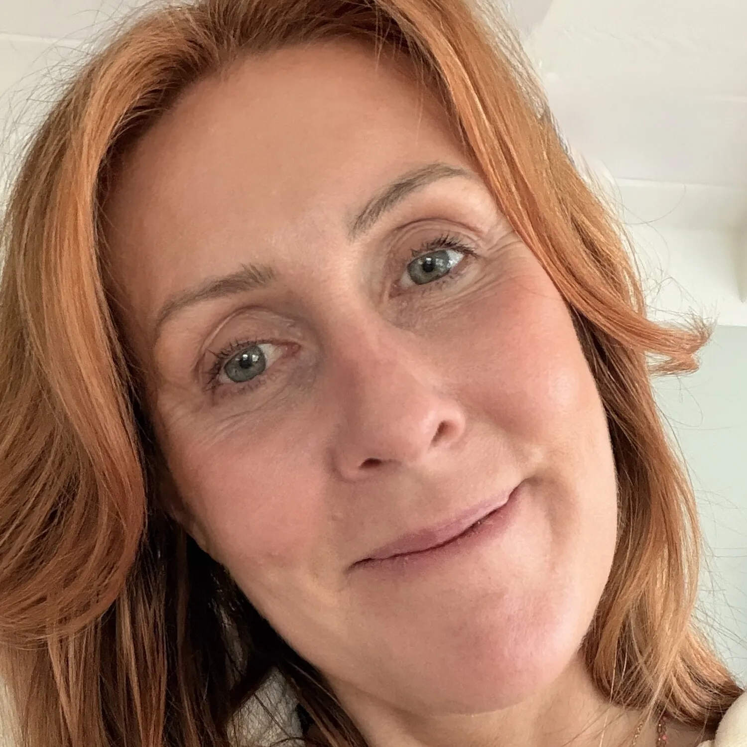Kenda Hansen, a close-up selfie with long copper hair and layered gold necklaces