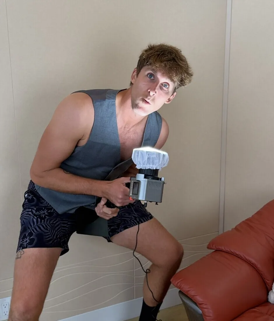 Kylen crouched in the studio holding a microphone, eyebrows up